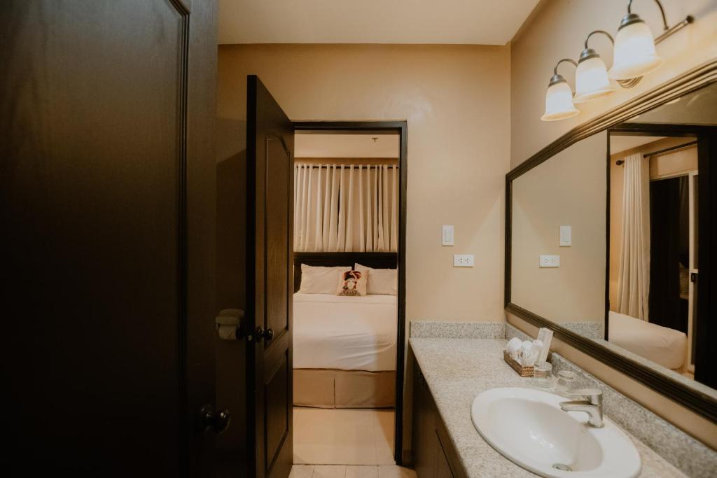 a bathroom with a sink and a mirror and a bed at Sta Barbara Residence Hotel in Cebu City