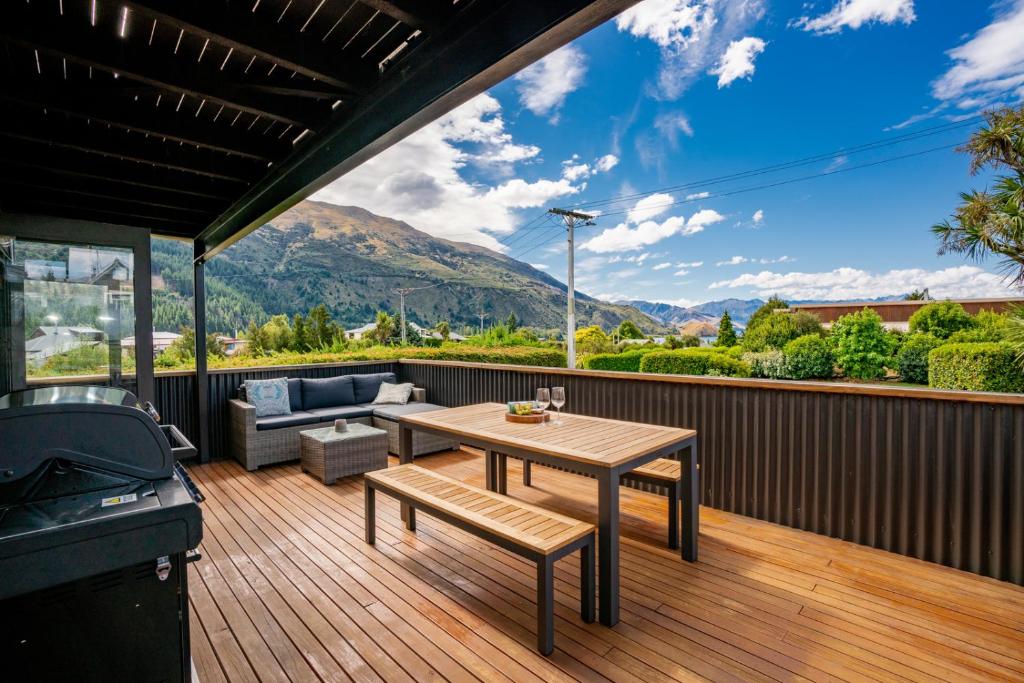 a patio with a table and a couch on a deck at Views on Parry - Lake Hāwea Holiday Home in Lake Hawea
