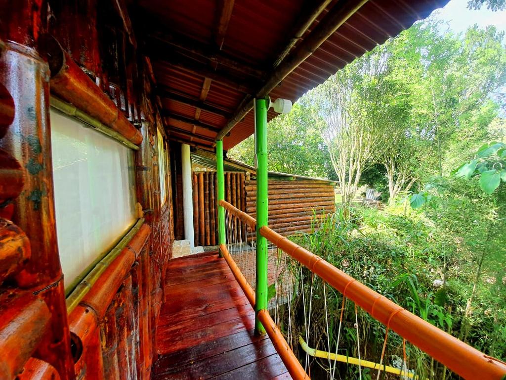 a porch of a house with green poles on it at Room in Lodge - Family Cabin With River View in Rizaralda