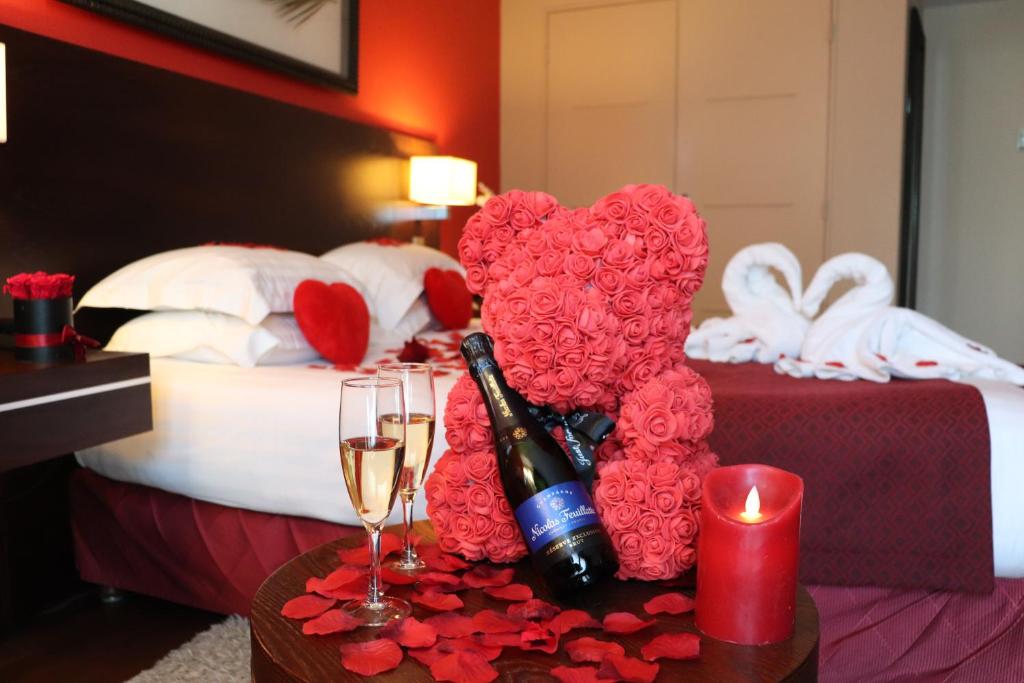 uma cama com um coração feito de rosas e taças de vinho em Hotel de Berny em Antony