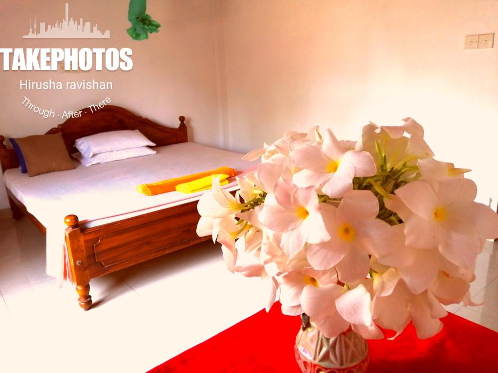 - une chambre avec un lit et un vase de fleurs dans l'établissement Golden Town Hotel, à Tangalle