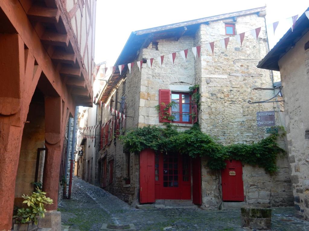 an alley with red doors and flags in an old building at Le logis d'Hestia in Billom