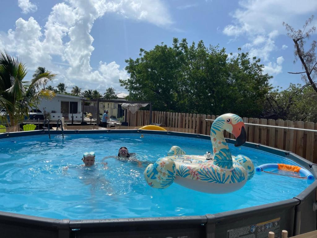 zwei Personen schwimmen in einem Pool mit einer aufblasbaren Ente in der Unterkunft Luna Bay Breeze in Marathon