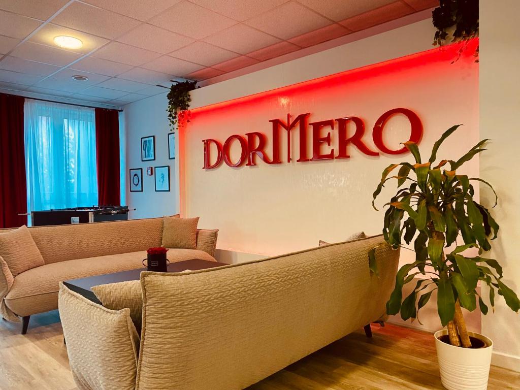 a waiting room with couches and a sign that reads donate at DORMERO Hotel Bretten in Bretten
