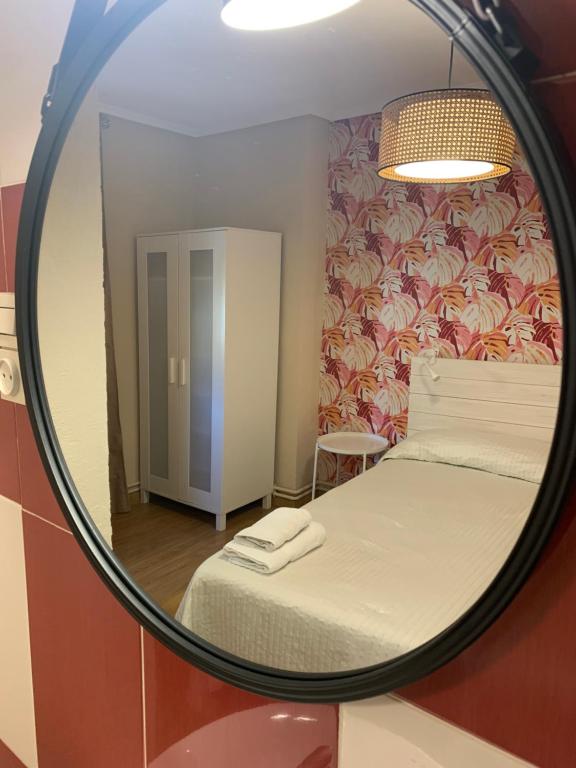espejo reflejo de un dormitorio con cama en Hosteria Tajahierro, en Reinosa