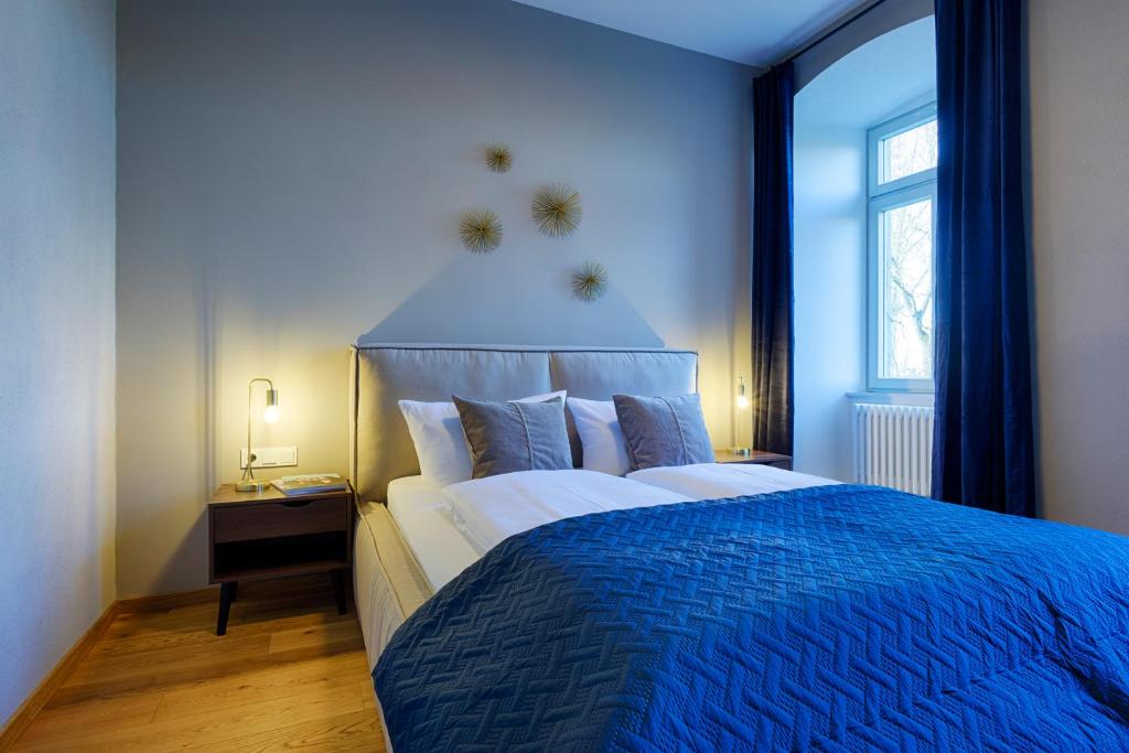 1 dormitorio azul con 1 cama grande con manta azul en Grimm's Schlossapartments Würzburg - by homekeepers, en Würzburg