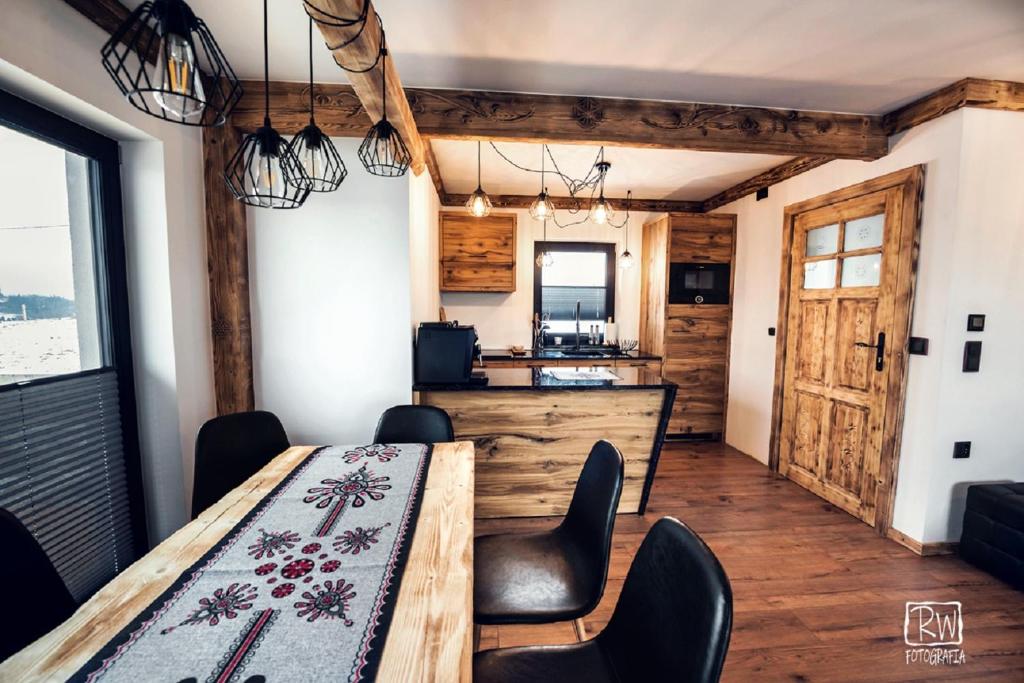 a kitchen and dining room with a table and chairs at Laura Resort - Luxury Chalets z jacuzzi in Szaflary