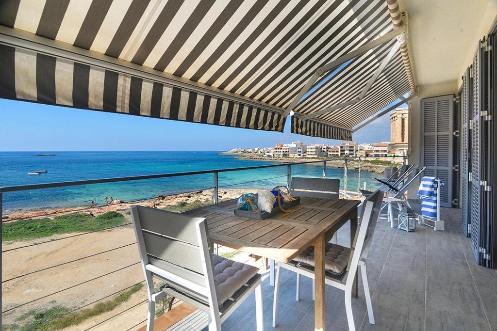 una mesa de madera y sillas en un balcón con vistas al océano en APARTMENT SES BAULES, en Colonia de Sant Jordi