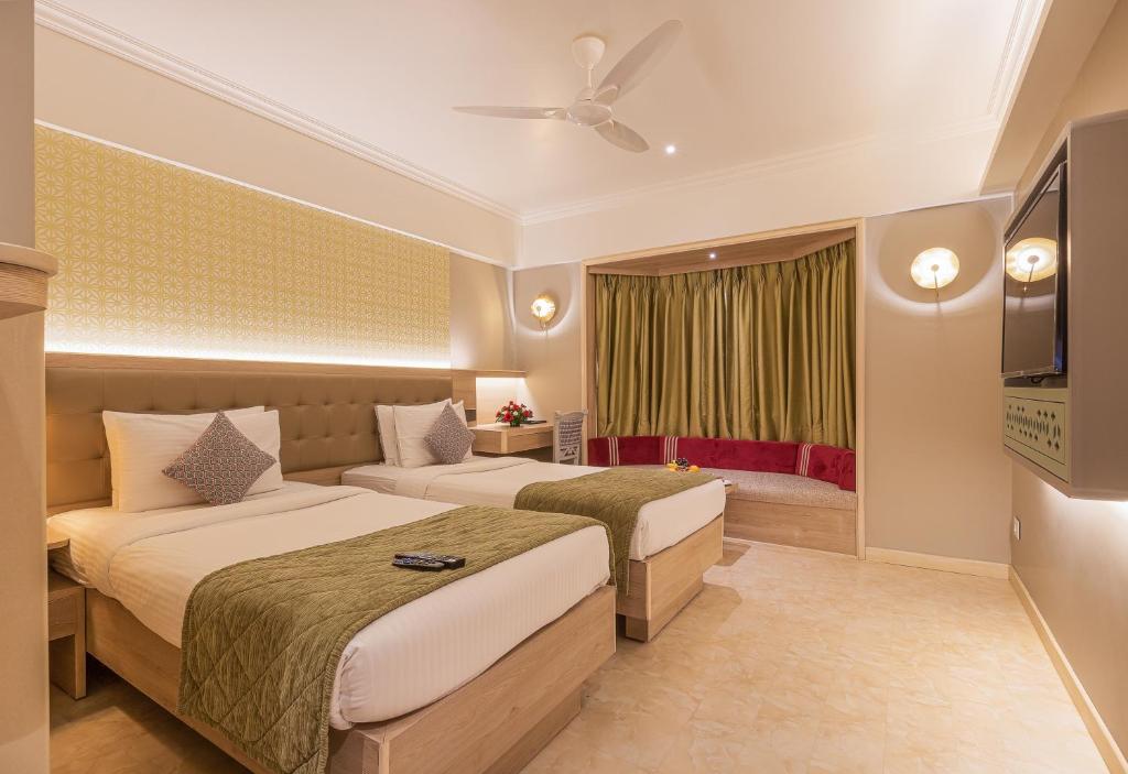 Cette chambre comprend deux lits et une télévision. dans l'établissement The Paradise By Tunga, à Mumbai