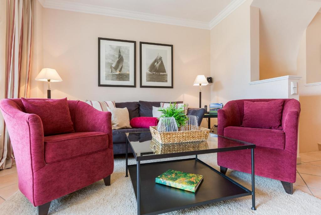 sala de estar con 2 sillas de color púrpura y mesa en Landhaus Weidenstieg App 2, en Wenningstedt