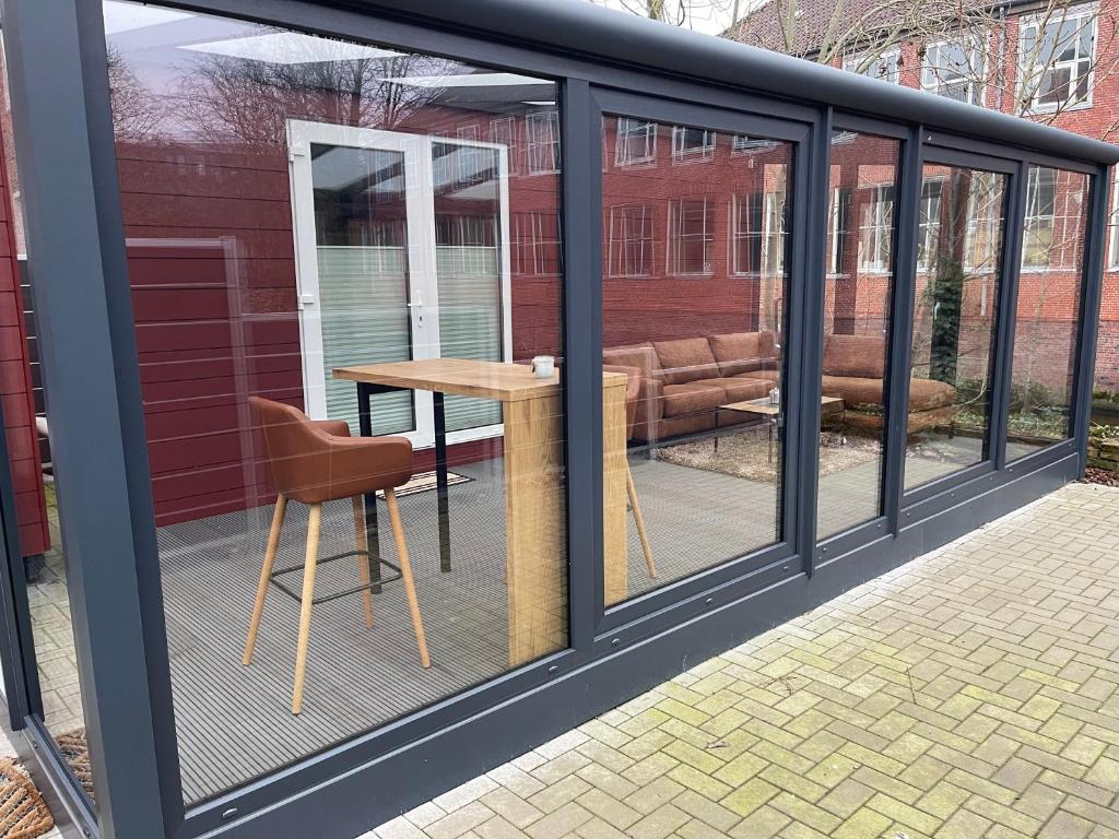 een afgeschermde veranda met een tafel en een stoel bij Möwenhaus in Emden