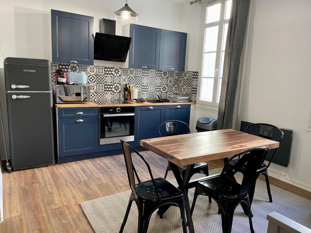 una cocina con armarios azules y una mesa de madera con sillas. en République - Dauder de Selva, en Perpiñán
