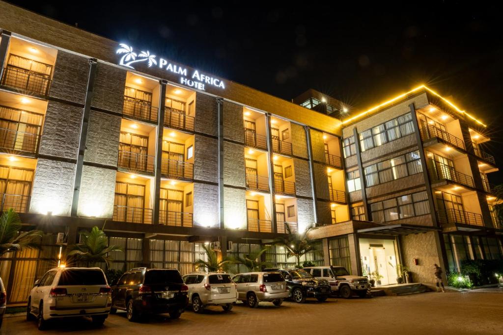 un edificio con coches aparcados delante de él por la noche en Palm Africa Hotel Juba en Yuba