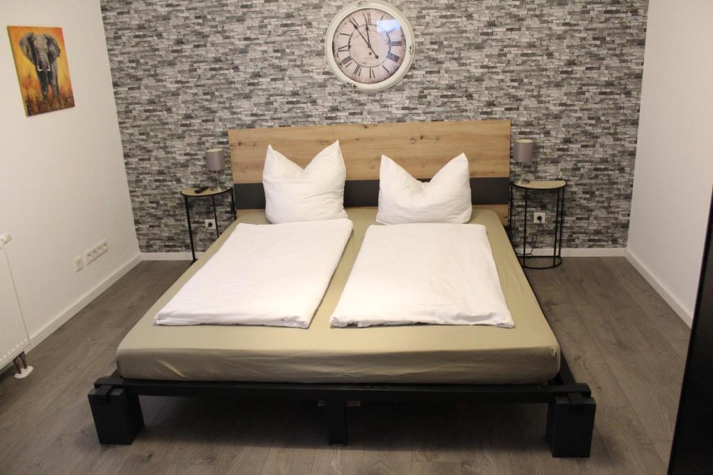 1 cama con 2 almohadas y reloj en la pared en Appartement Luna, en Ruppach-Goldhausen