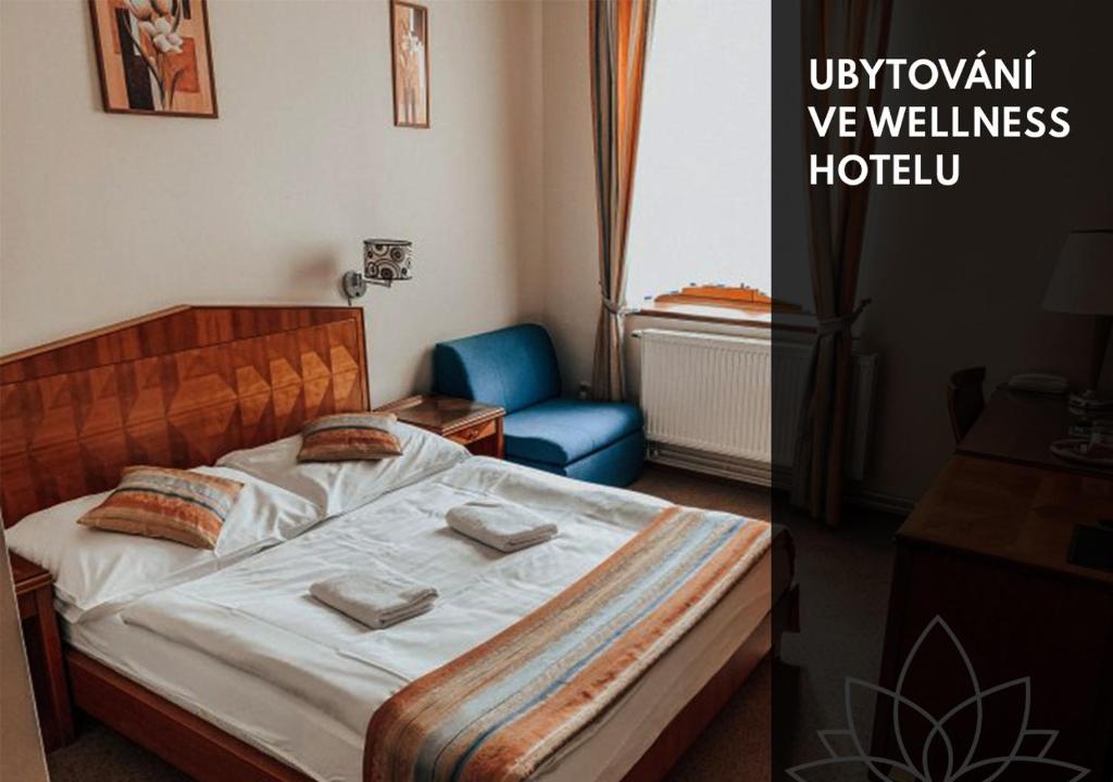 1 dormitorio con 1 cama y 1 silla azul en Wellness Hotel Kolštejn, en Branná