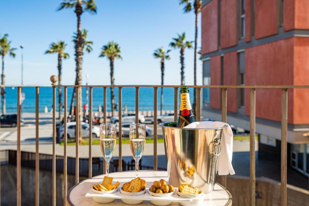a table with two glasses of wine and food on a balcony at Kronos on the Beach suite 1 in Barcelona