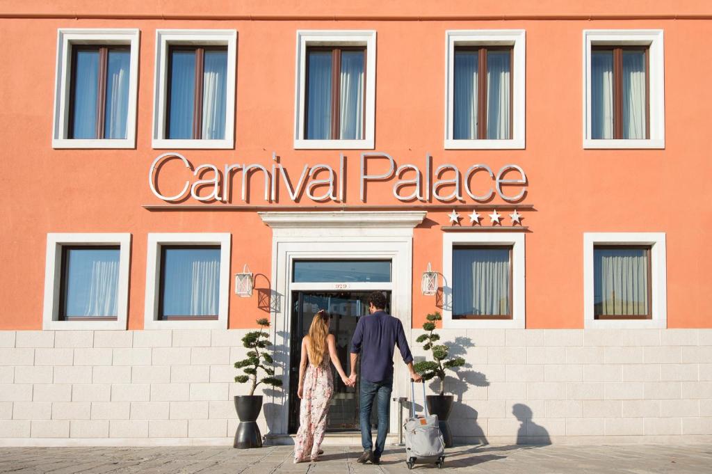 a man and a woman walking in front of a building at Carnival Palace - Venice Collection in Venice