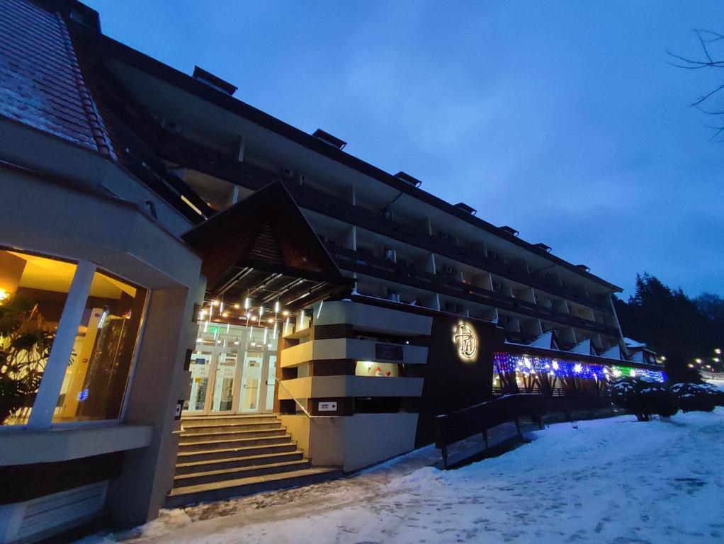 a building in the snow at night with lights at Hotel Ciucas in Băile Tuşnad