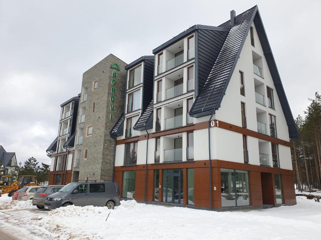 a building with a solar roof in the snow at Apartman Borovi Divčibare in Divčibare