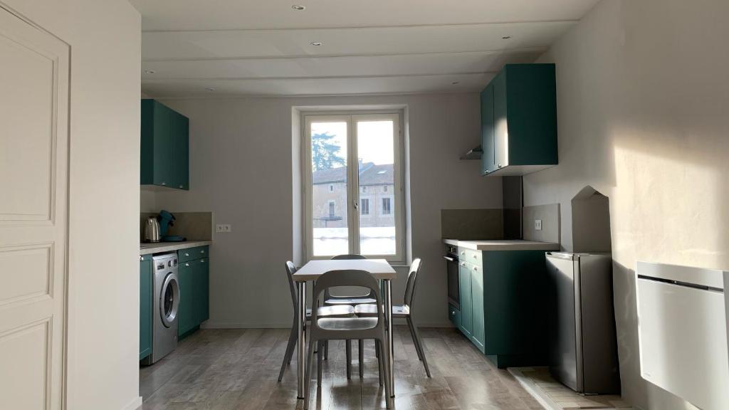 a kitchen with green cabinets and a table and chairs at La Source in Saint-Martin-lʼArs