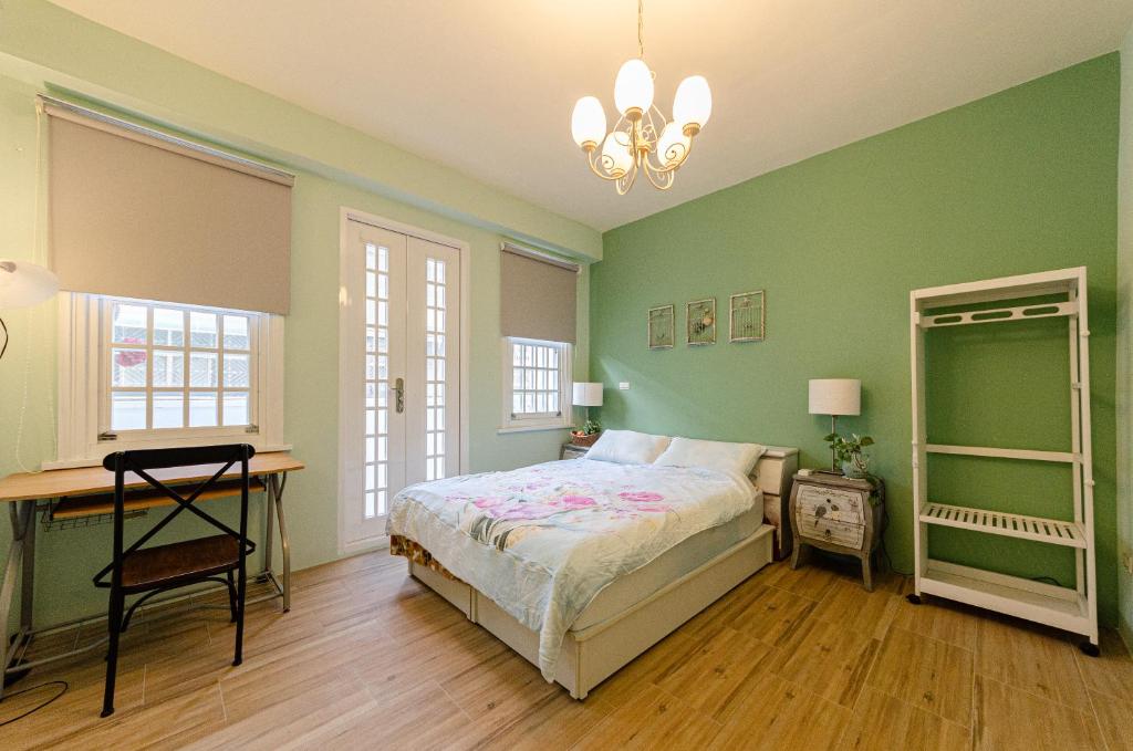 埔里鎮的住宿－埔里歐亞包棟民宿，一间卧室设有绿色的墙壁、一张床和一张书桌