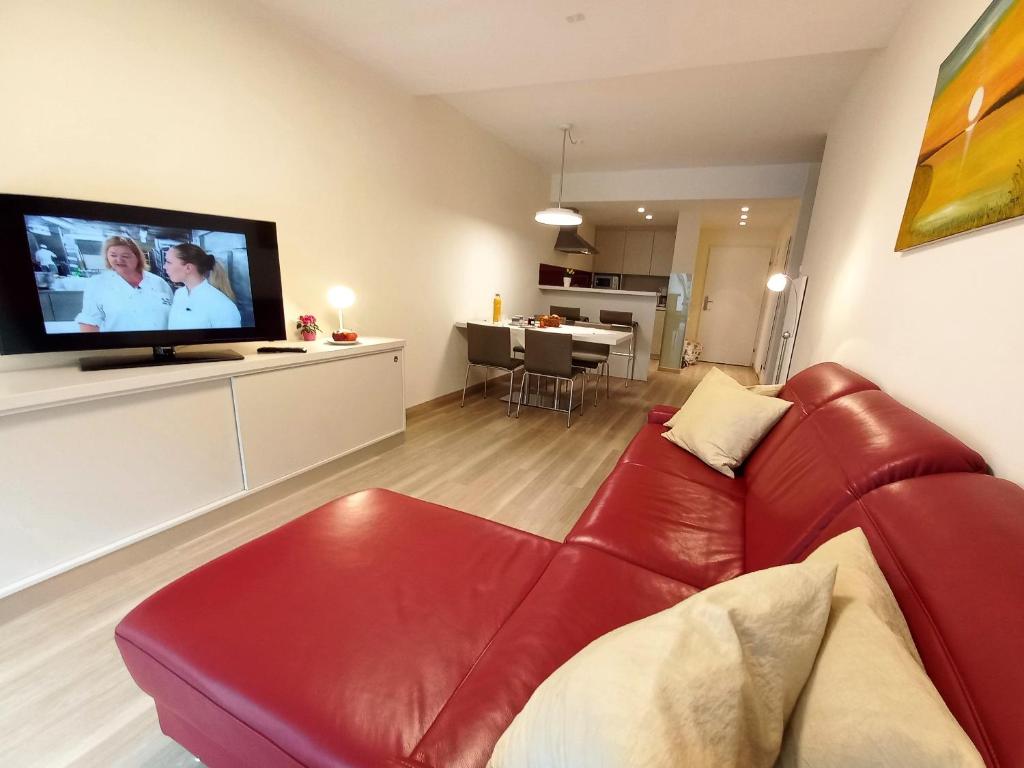 un soggiorno con divano rosso e TV a schermo piatto di LB2 Seeappartement Haus Landskron direkt am Ossiachersee a Landskron