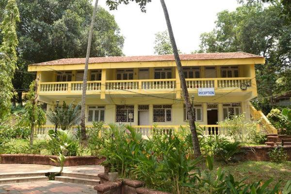 a yellow house with a balcony in a garden at Mayem Lake View in Maem