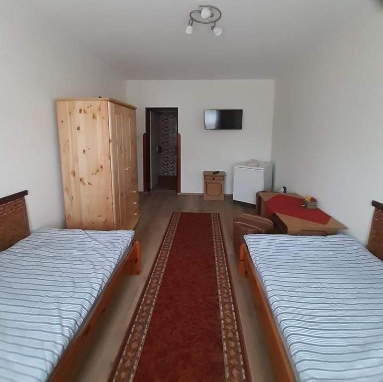 ハイドゥソボスローにあるPegazus Vendégházのベッド2台と壁掛けテレビが備わる客室です。