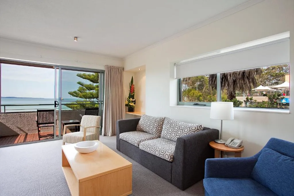A living room with a sofa, balcony chairs and a view of the bay