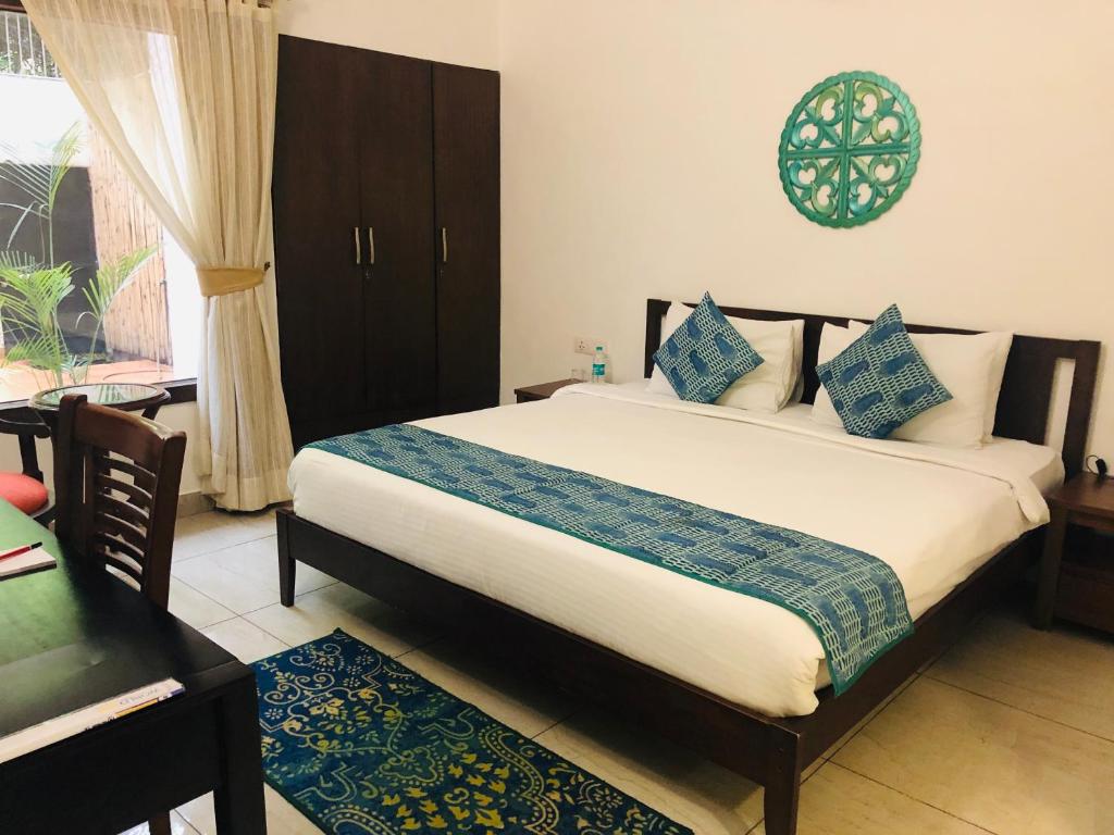 um quarto com uma cama, uma mesa e uma janela em The Neem em Nova Deli