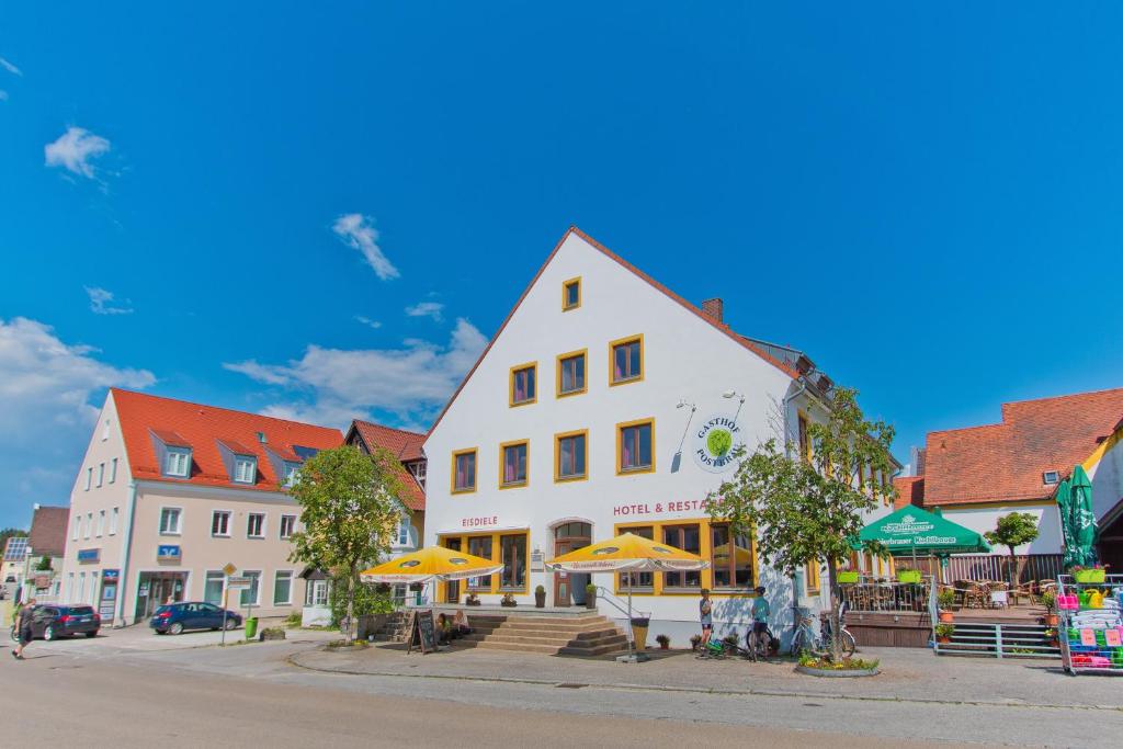 a large white building with umbrellas in a town at Gasthof Postbräu in Siegenburg