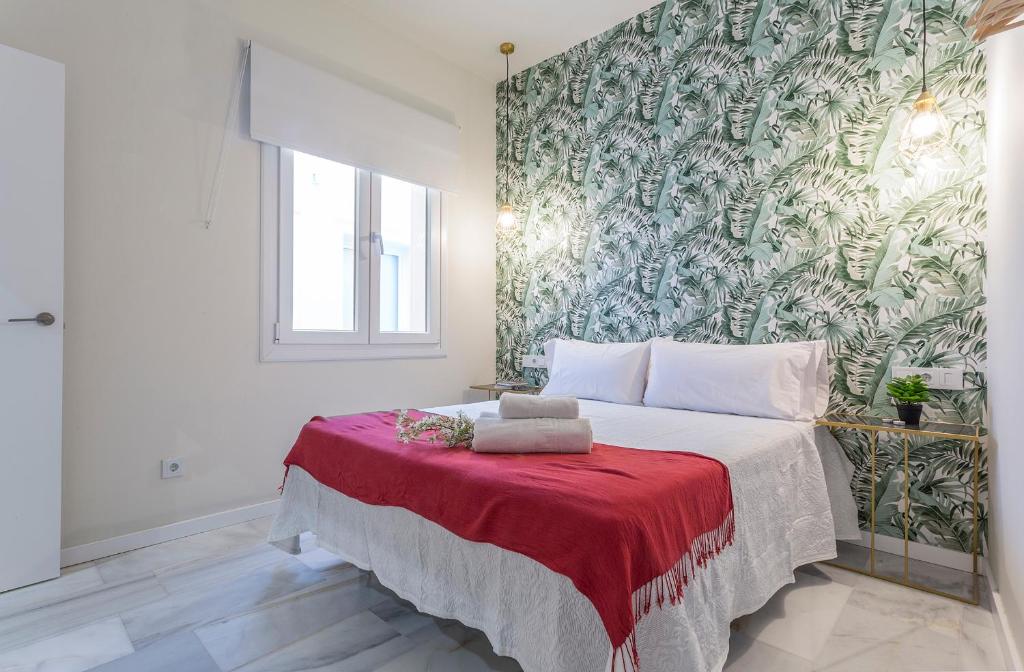 LaLa Suites Corredera Centro في خيريز دي لا فرونتيرا: غرفة نوم بسرير كبير مع بطانية حمراء
