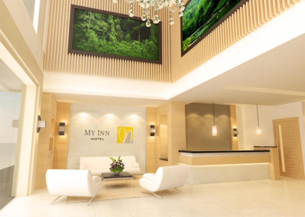 un vestíbulo de un hotel con muebles blancos y una lámpara de araña en My Inn Hotel Lahad Datu, Sabah en Lahad Datu