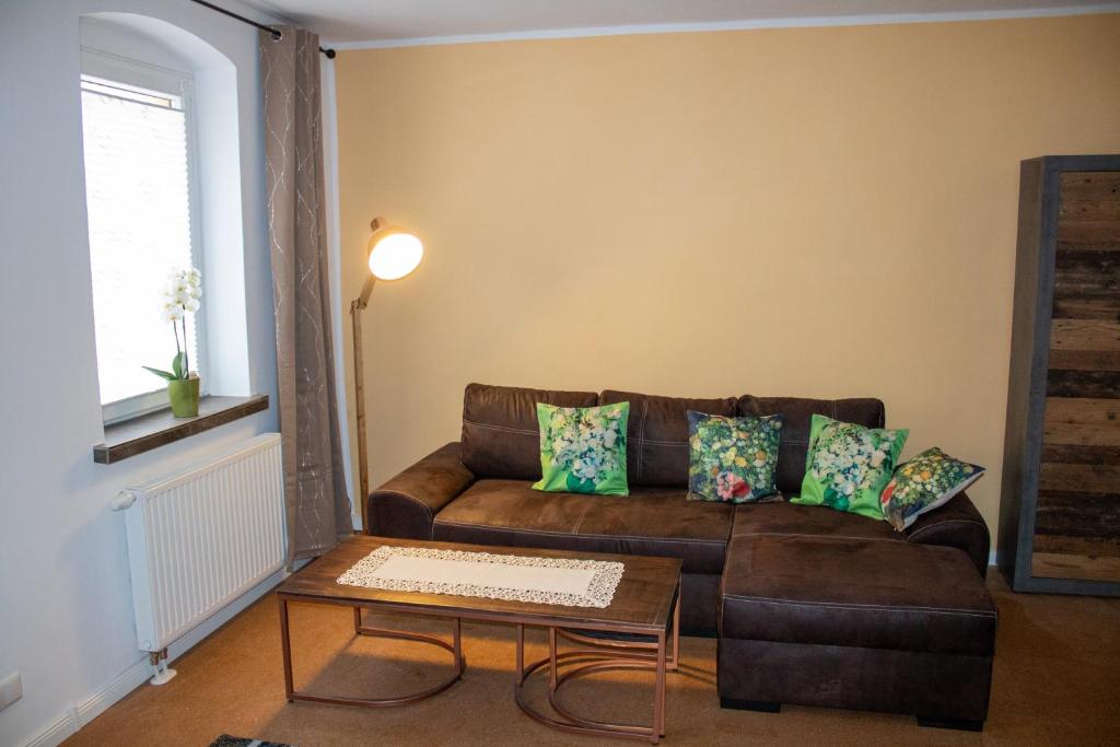 ein Wohnzimmer mit einem braunen Sofa und einem Tisch in der Unterkunft Altstadtidyll 60qm - Central - Parking - Washer in Haldensleben