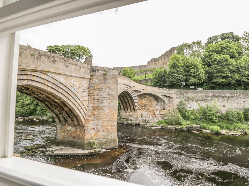 an old stone bridge over a river at 1 The Riverside in Barnard Castle