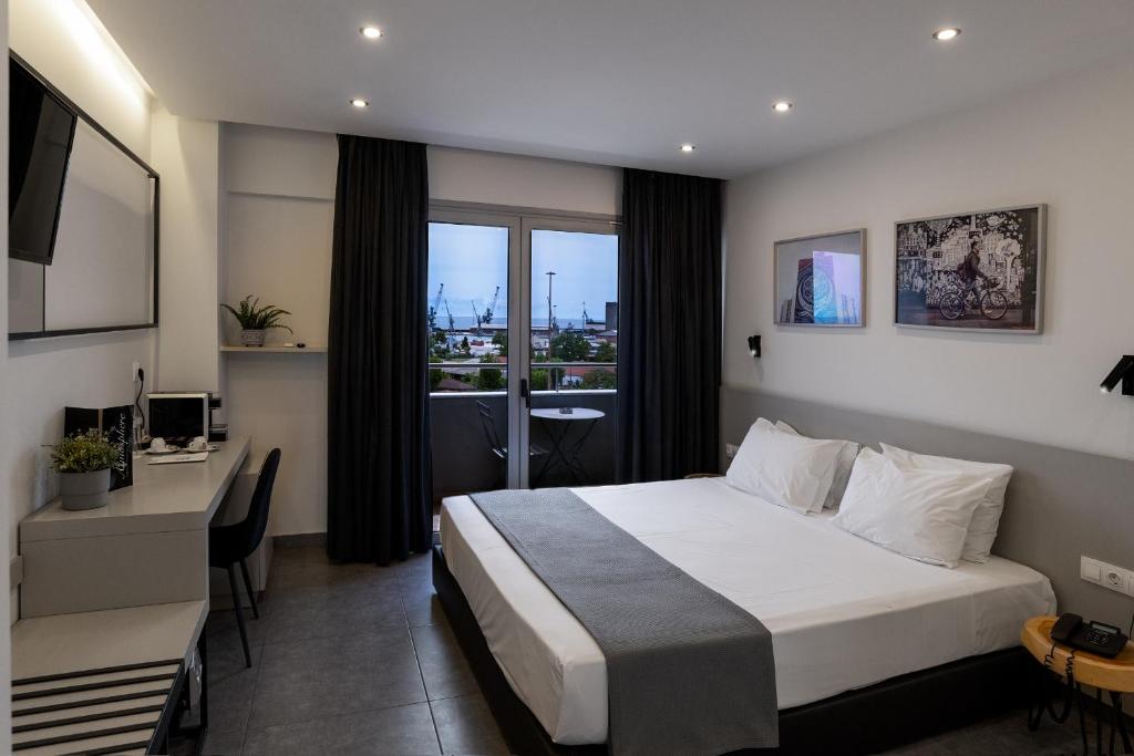 a hotel room with a bed and a desk and a window at White Luxury in Thessaloniki