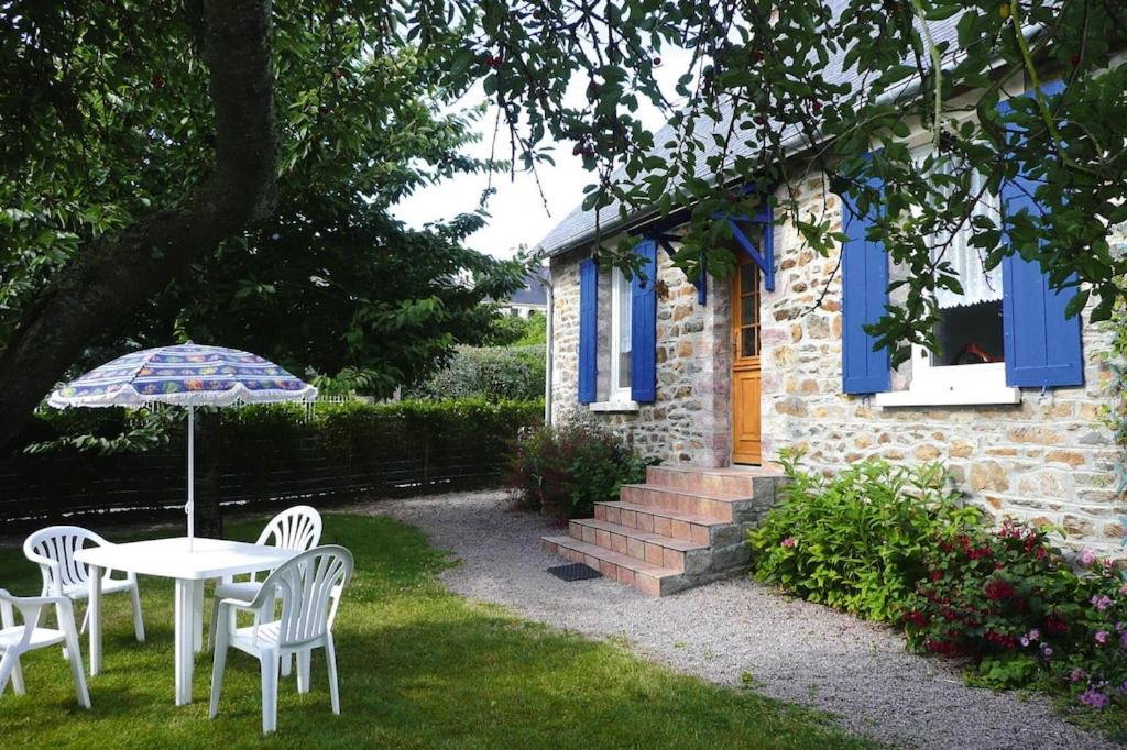 - une table et des chaises avec un parasol en face d'une maison dans l'établissement Holiday home, Pléneuf-Val-André, à Pléneuf-Val-André