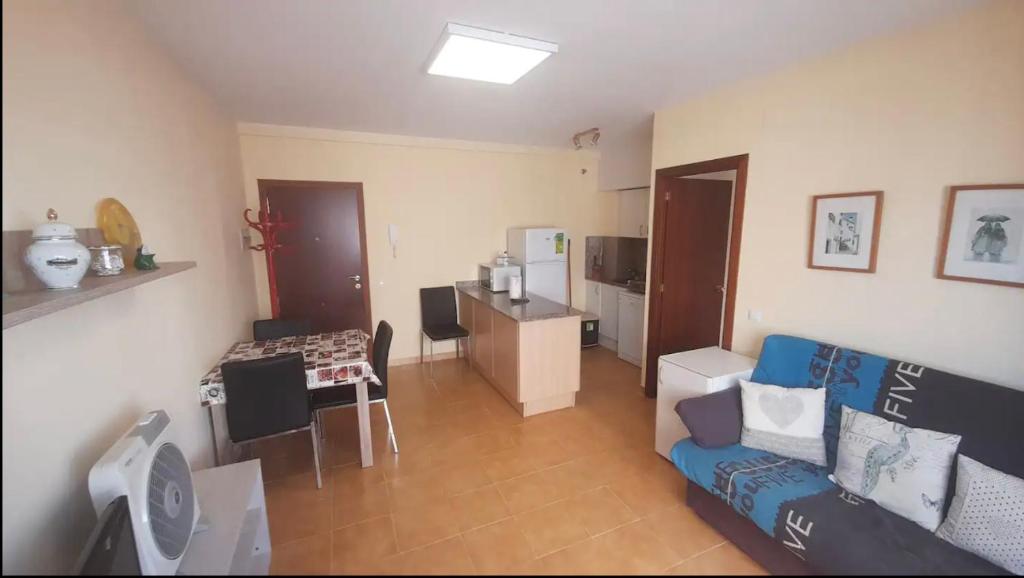 uma sala de estar com um sofá azul e uma cozinha em Alex Apartament em Sant Antoni de Calonge