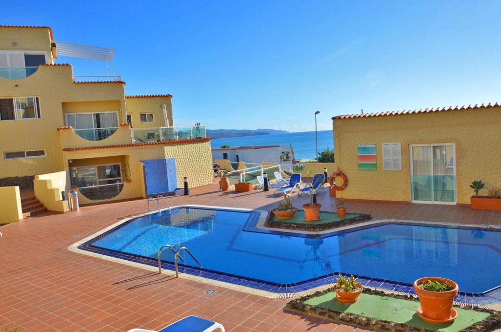 a swimming pool in front of a house at Ferienwohnung PLAYA - Pool - 50 m Strand - Meerblick - WiFi in Costa Calma