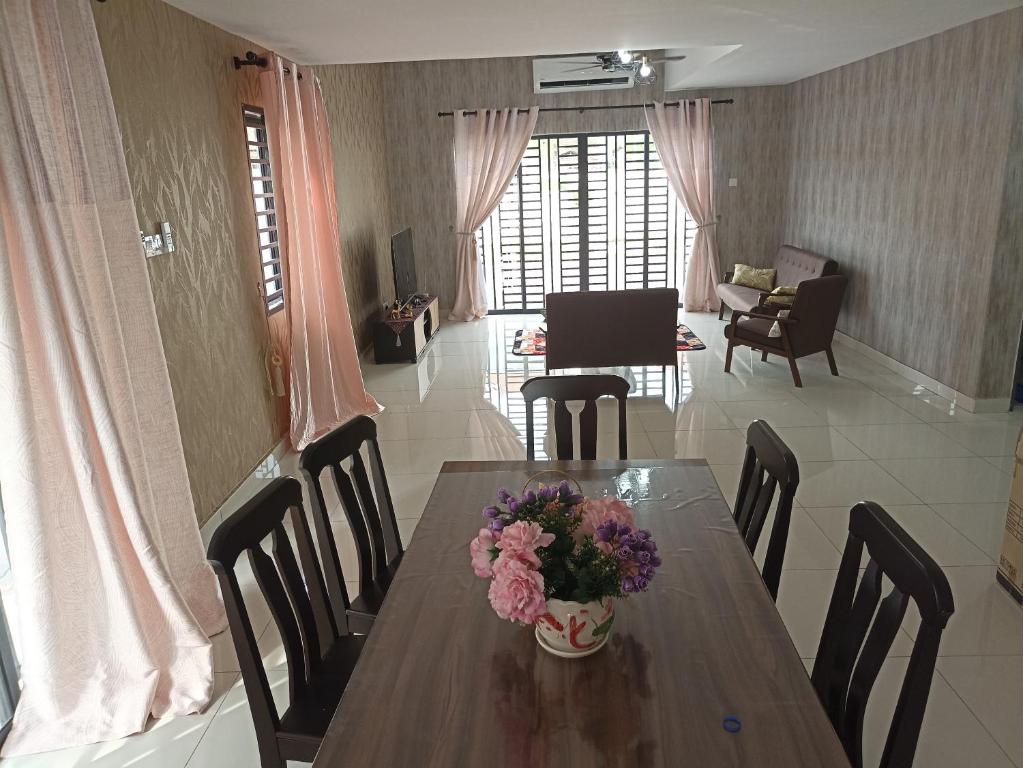 a dining room table with a vase of flowers on it at Mulberi Homestay 4BR 3Bth(8-10 px) in Port Dickson