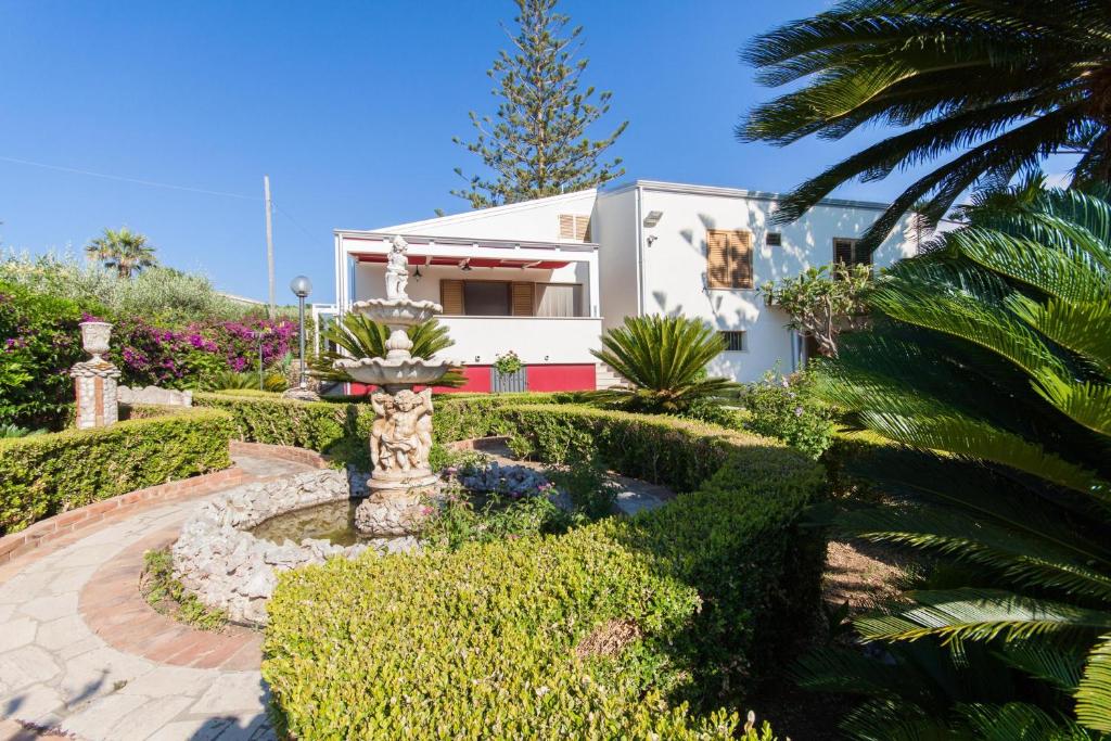 ein Haus mit einem Brunnen inmitten eines Gartens in der Unterkunft Casa Blu in Castellammare del Golfo