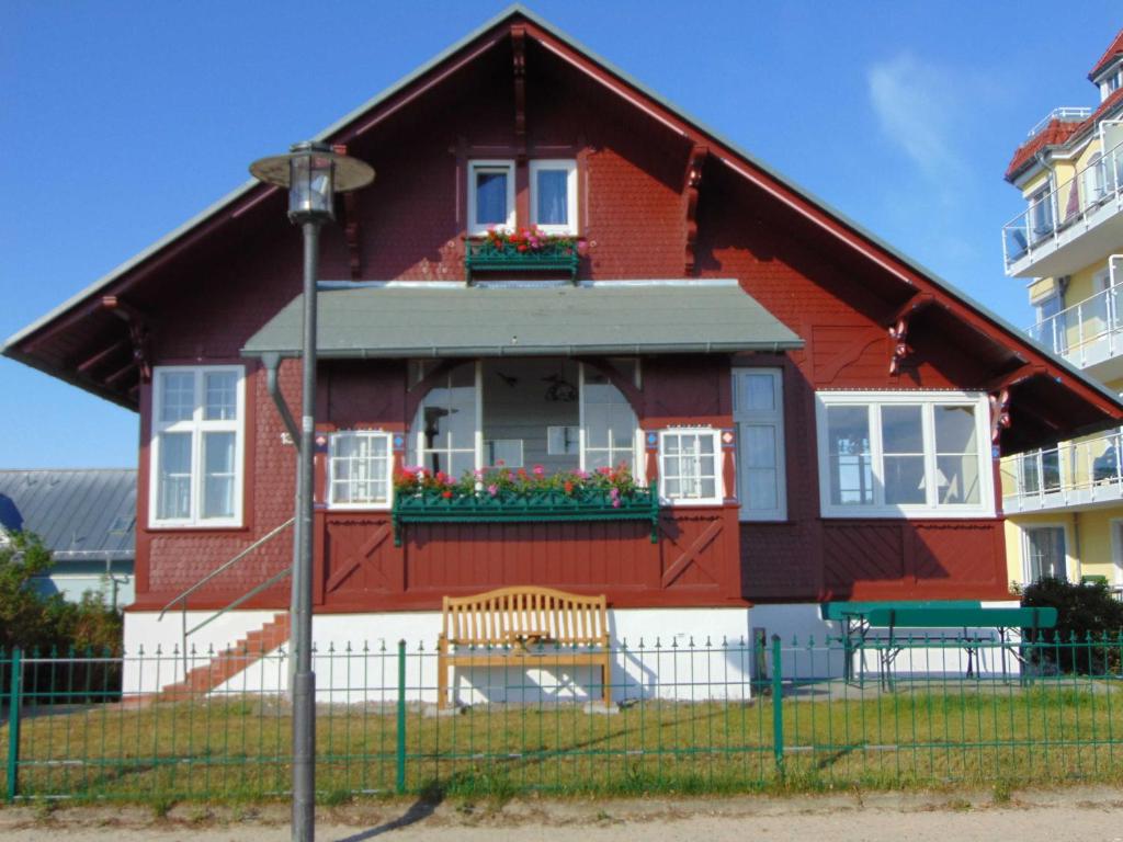 een rood huis met een raam en bloemen erop bij Strandvilla Whg 01 in Bansin