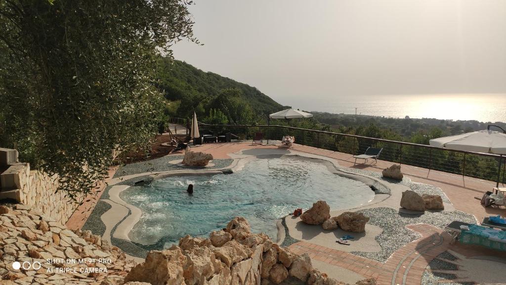 a swimming pool with rocks in it next to the water at Il Corbezzolo Tropea Residence in Tropea