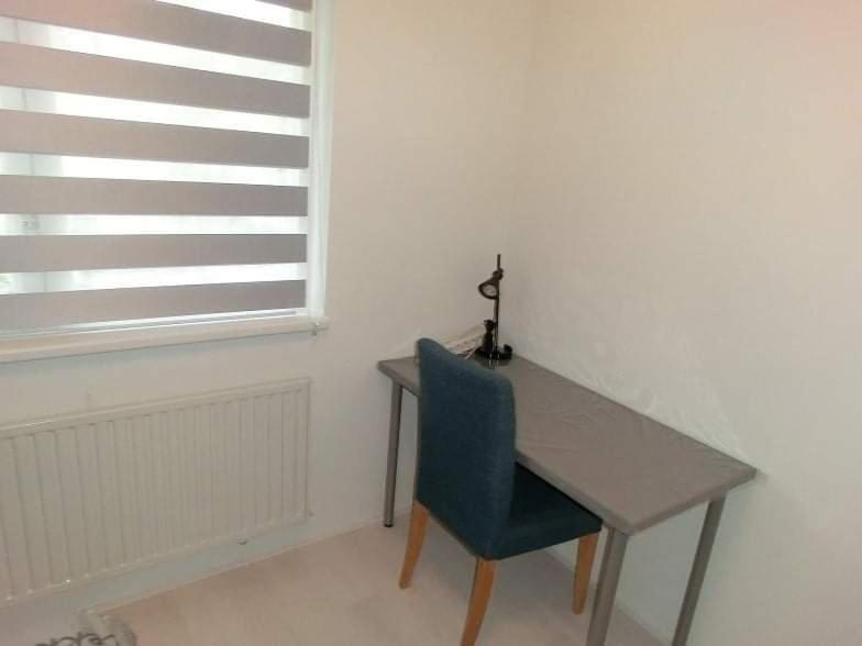 a desk in a room with a blue chair and a window at lovely propertys in Bucharest