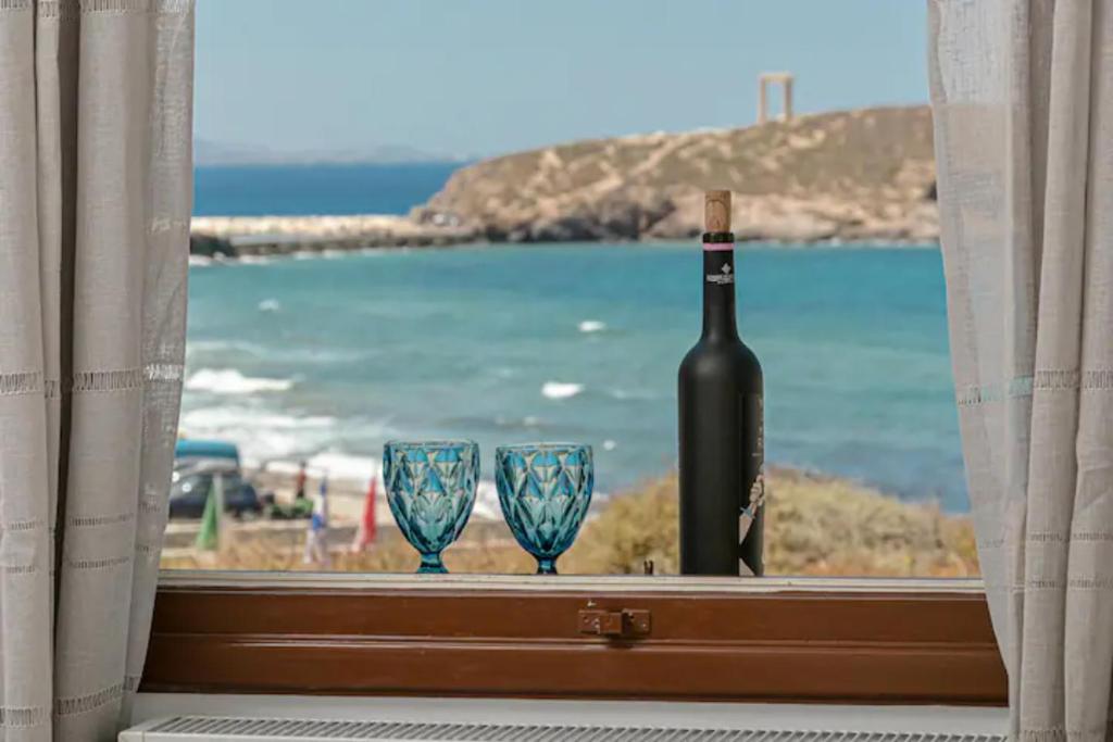 a bottle of wine and two glasses in a window at Calma Home in Naxos Chora