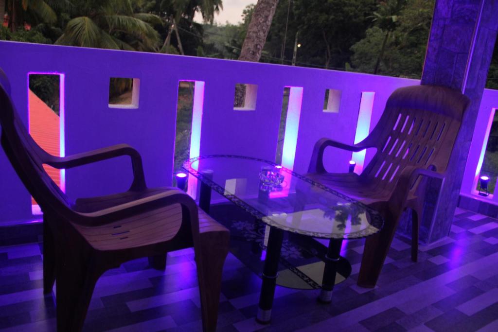 2 chaises et une table sur une terrasse avec des lumières violettes dans l'établissement Sandaru Holiday Resort, à Weligama