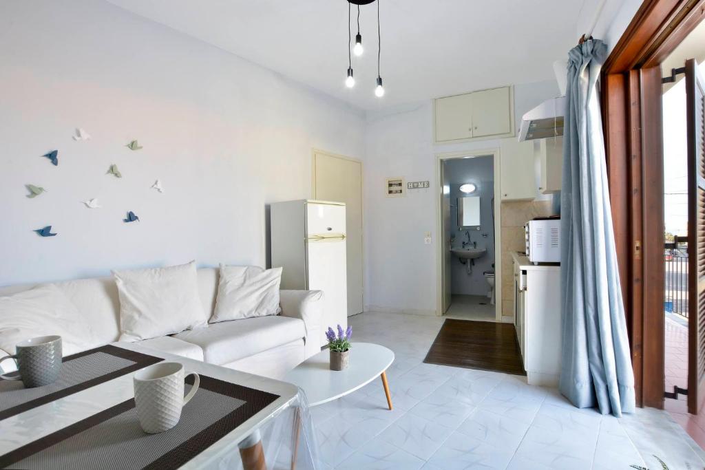 Roberto's Apartments في رودا: غرفة معيشة بيضاء مع أريكة وطاولة