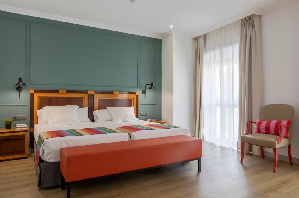 a bedroom with a large bed and a chair at Hotel Don Curro in Málaga