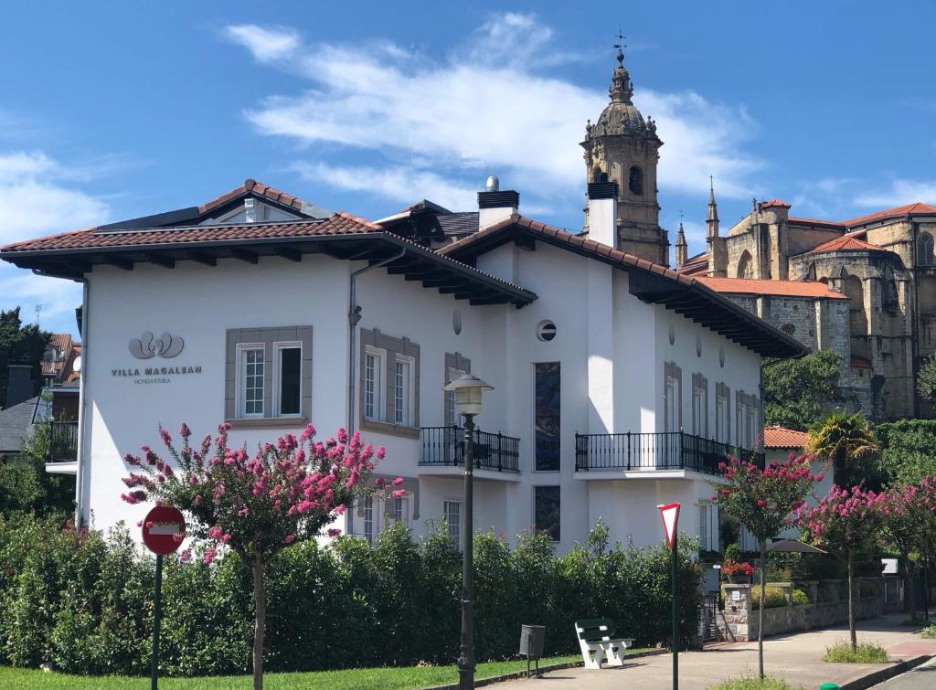 un bâtiment blanc avec une tour d'horloge en arrière-plan dans l'établissement Villa Magalean Hotel & Spa, à Fontarrabie