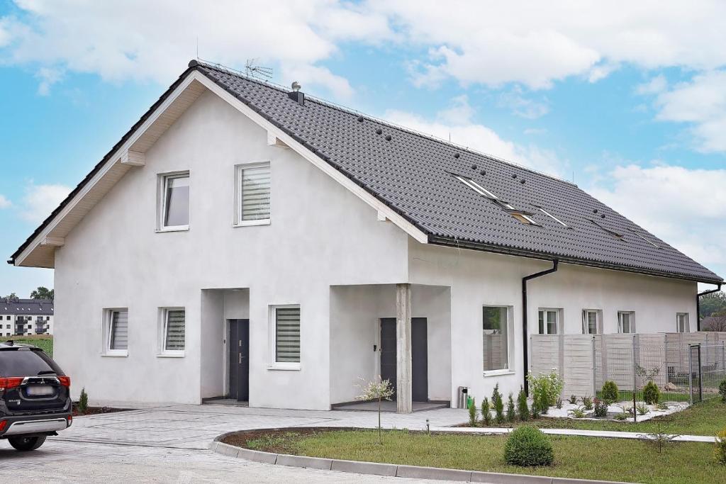 una casa blanca con techo negro en Zielona Dolina 2020, en Smolice